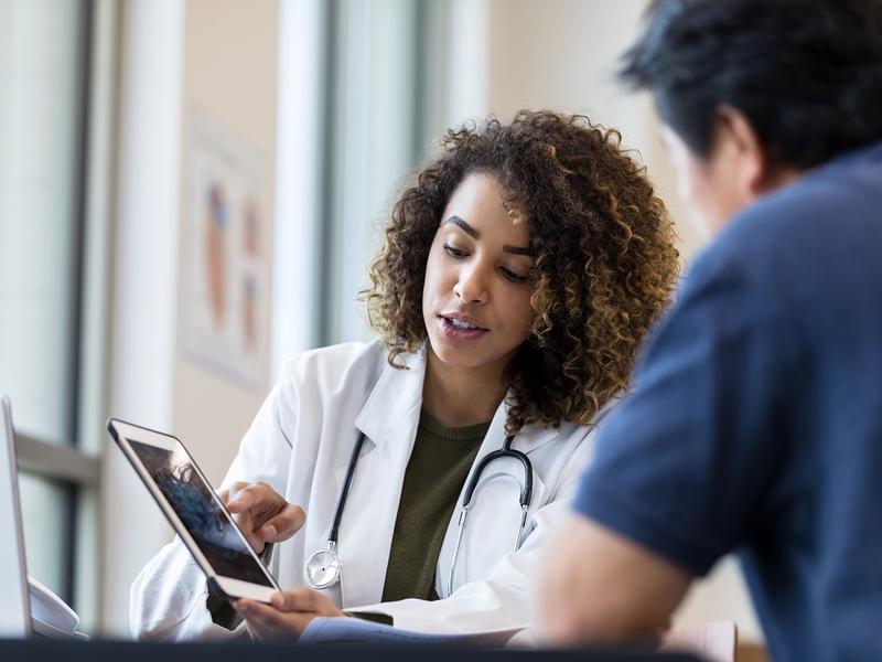 Woman doctor showing man an image on tablet.