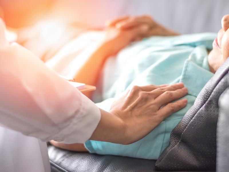 Image of patient in bed with doctor's hand on shoulder.