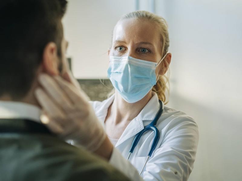 female physician examining a patient, while wearing a mask