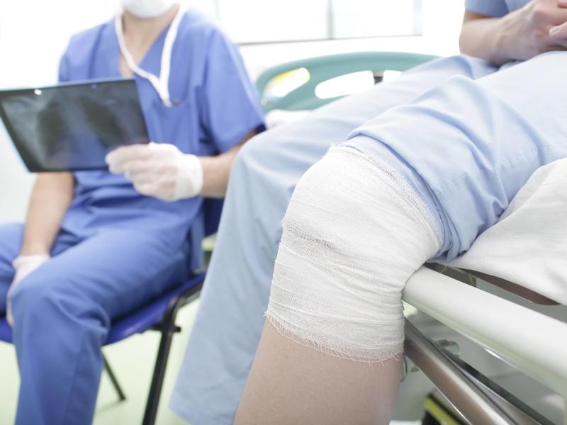 person with their knee wrapped up, meeting with a physician